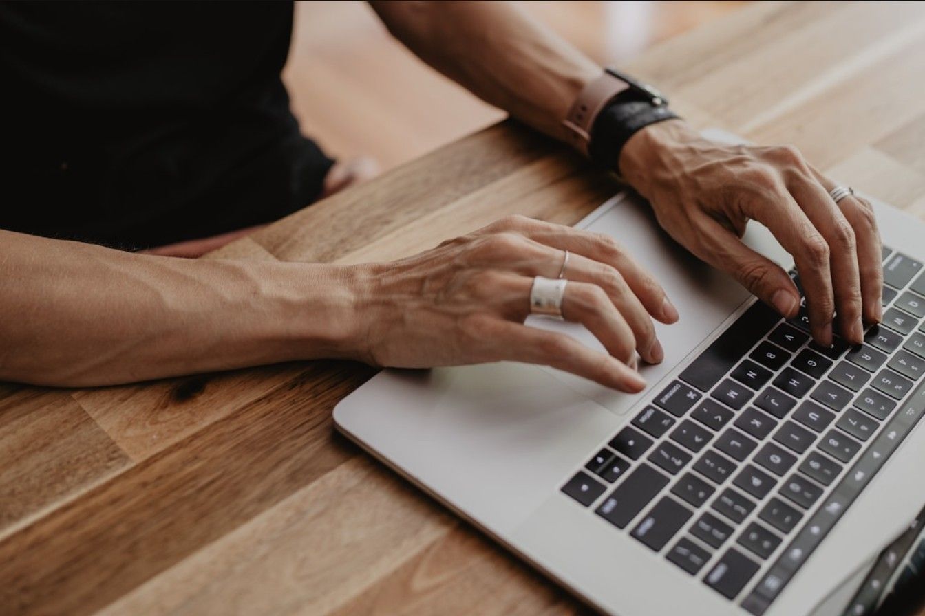 Close-up of hands typing on a laptop keyboard at a wooden desk, representing a business buyer completing an online checkout